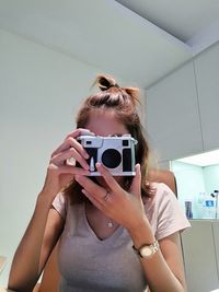 Woman photographing with camera at home