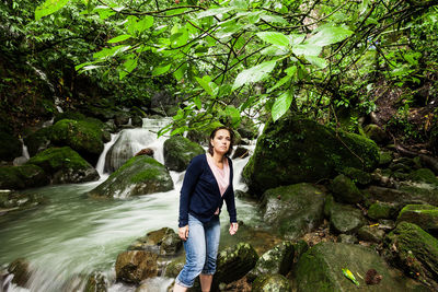 Woman standing on rock against trees in forest