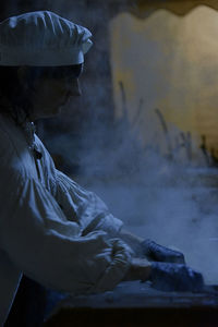 Side view of man sitting on window