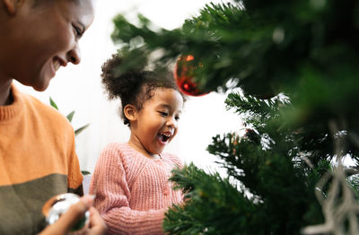 Mother and daughter holding decoration on christmas tree