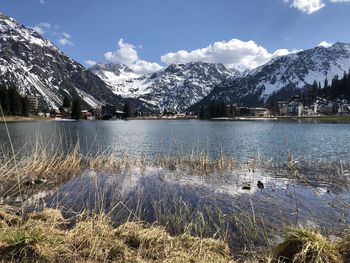 Scenic view of lake by snowcapped mountains against sky