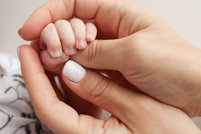 Cropped hand of person with nail polish against white background