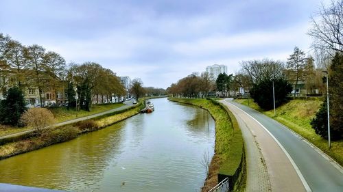 Road by river in city against sky