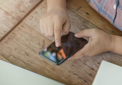 Midsection of person using mobile phone on table