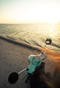 Deck chairs on beach against sky during sunset