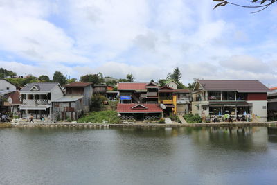 Buildings by river against sky