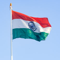 Low angle view of flag against blue sky