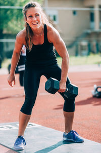 Woman lifting dumbbell on running track