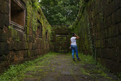 Rear view of woman standing by old wall