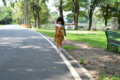 Rear view of woman standing on road amidst trees