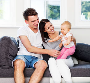 Happy friends sitting on sofa at home