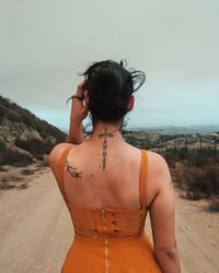 Rear view of woman standing at beach against sky