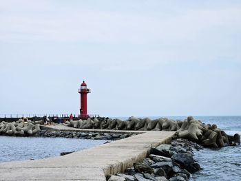 Lighthouse by sea against sky