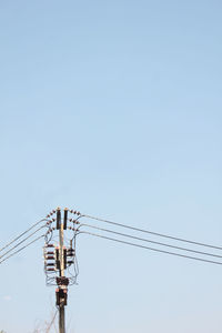 Low angle view of electricity pylon against clear sky