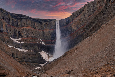 Beautiful cascades of hengifoss falling from mountains against dramatic sky