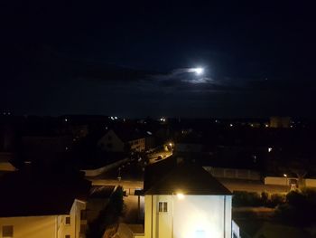 Illuminated buildings in town against sky at night