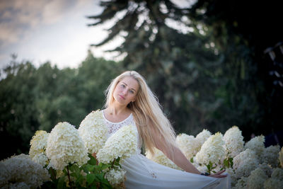 Portrait of smiling young woman against trees