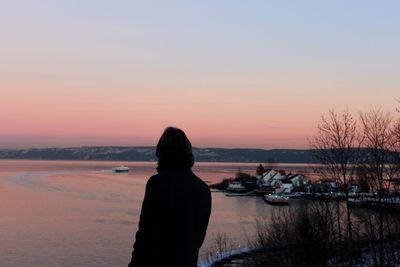 Silhouette man looking at sea against sky during sunset