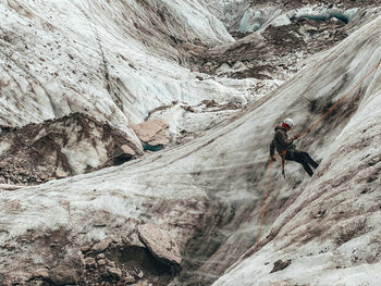 Close shot of mountaineer rappelling on glacier in european alps