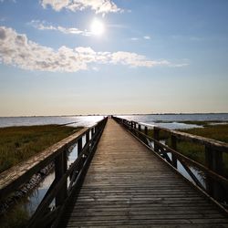 Boardwalk leading towards sea against sky