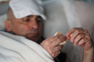 Close-up of man having orange while lying on sofa