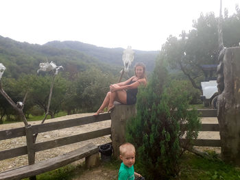 Full length of shirtless boy on plants against trees