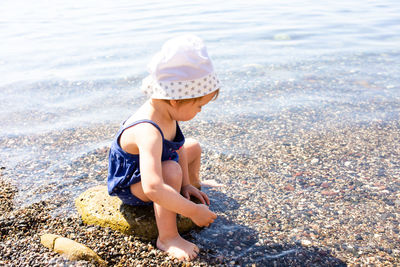 Little cute child girl playing on the seashore in summer