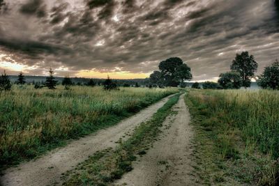 View of field against cloudy sky