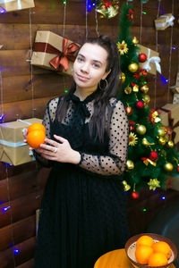 Portrait of young woman holding christmas tree