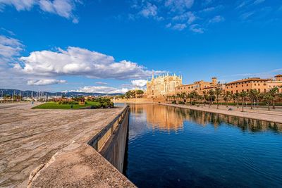 Scenic view of river by buildings against blue sky