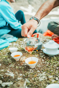 Low section of man pouring tea while sitting at beach