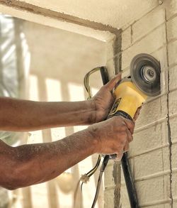 Midsection of man holding bottle against wall