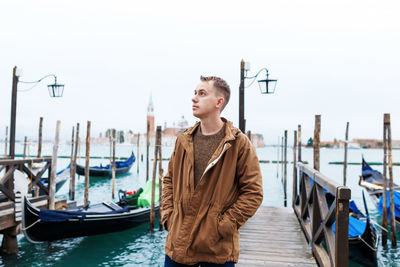 Young blond guy in a brown jacket in middle of streets of venice