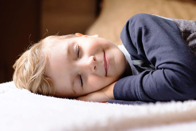 Cute kid relaxing while napping on a bed.