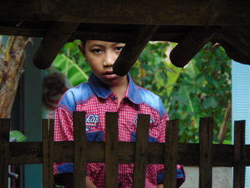 Portrait of boy looking through fence