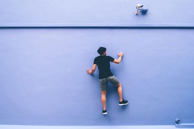 Full length of man climbing on wall