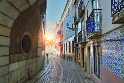 Alley amidst buildings during sunset