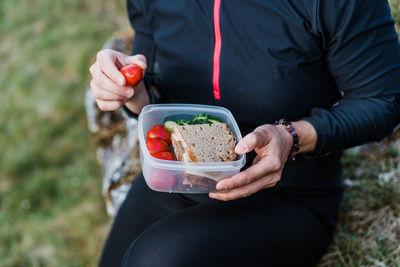 Woman holding a container with snacks with bread and vegetables during a hike