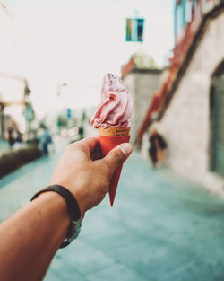 Cropped hand of man holding ice cream cone on street