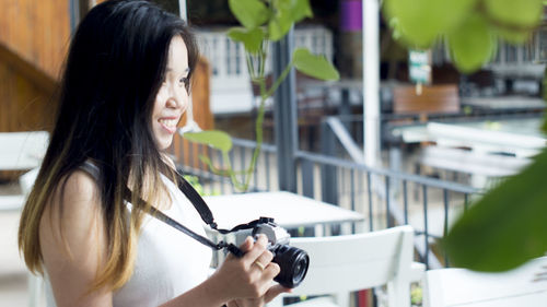 Portrait of a smiling young woman holding camera