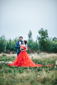 Couple kissing on field against sky