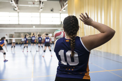 Competitive female volleyball player serving ball while tourname