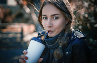 Portrait of young woman drinking outdoors