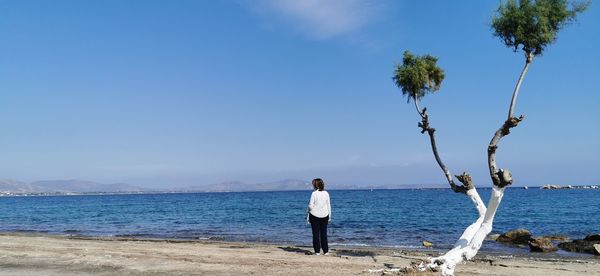 Rear view of woman standing on beach against sky