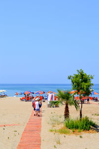 People at beach against clear sky