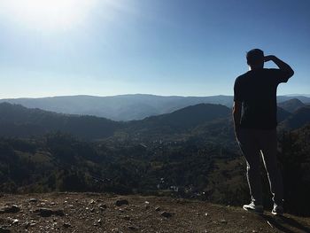 Rear view of man looking at mountain against sky