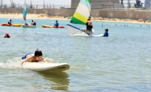 Shirtless boy surfboarding in sea