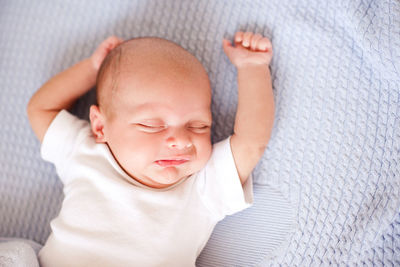 Cute baby boy stretching arms on bed at home