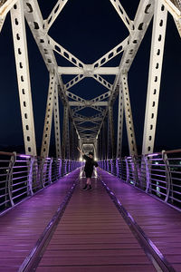 Woman standing on footbridge at night