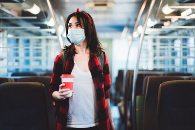 Woman holding mobile phone while standing in bus